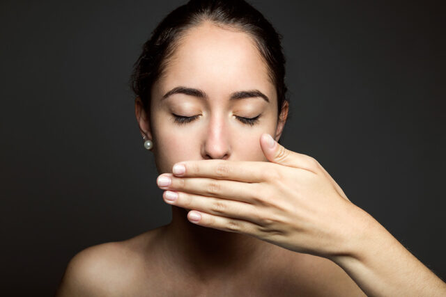 beautiful young woman covering her mouth with hand isolated
