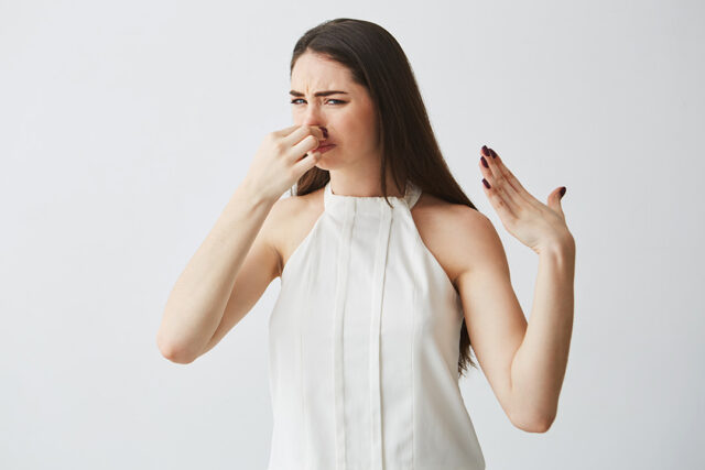 young brunette girl closing covering nose bad smell